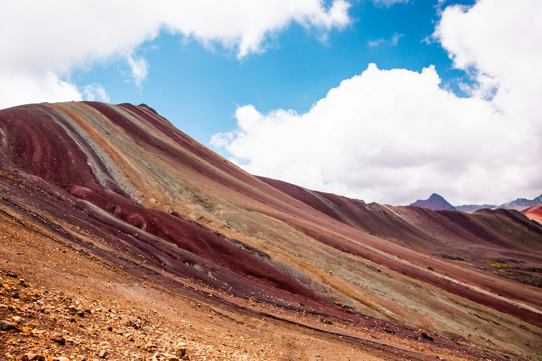 The striped slopes of Vinicunca, Rainbow Mountain, under a blue sky