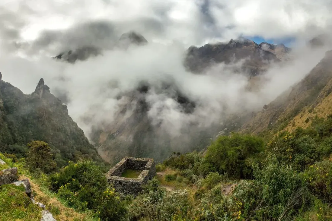 Inca stone ruins beside a cloud-filled valley on the Inca Trail